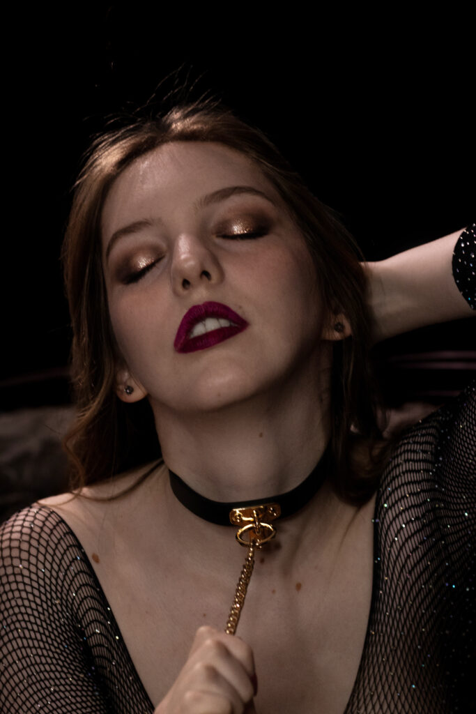 IMG_0226 A moody boudoir portrait of a woman's face her head arched back with a collar on her neck in michigan