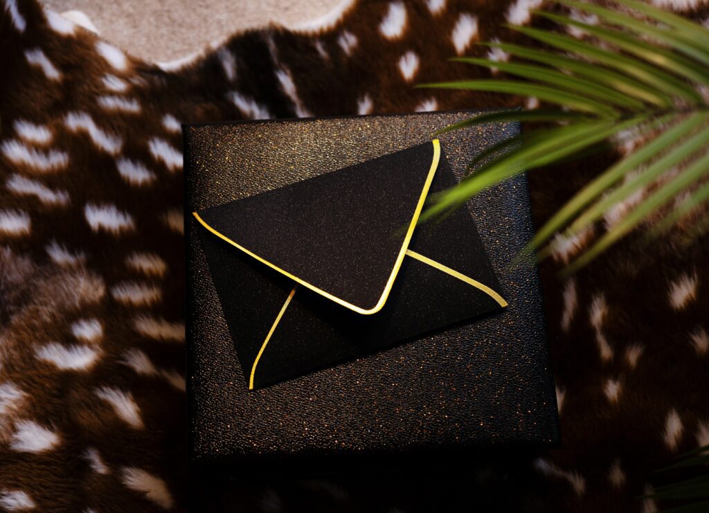 Black glitter envelope holding petite boudoir polaroids from a luxury boudoir experience in Michigan