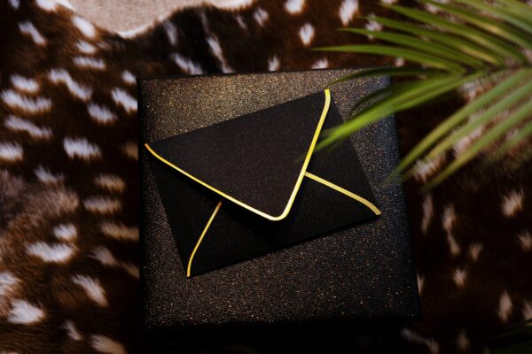 A22A2381 Black glitter envelope holding petite boudoir polaroids from a luxury boudoir experience in Michigan